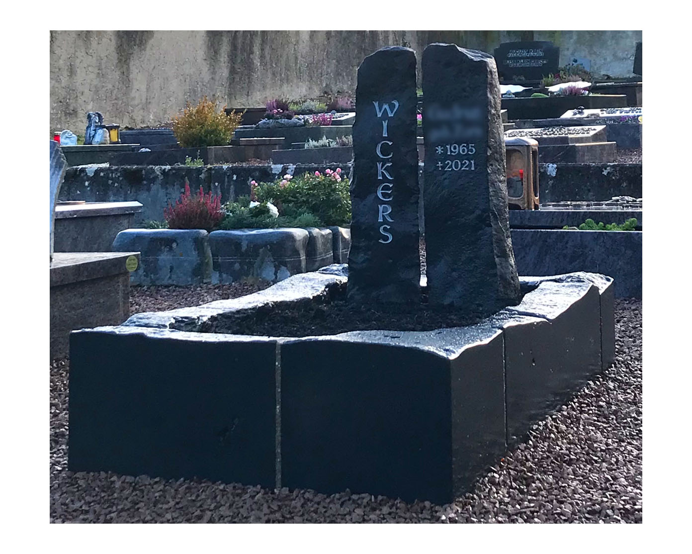 Zweiteiliges Grabmal aus dunklem Hartgestein mit passender Grabeinfassung